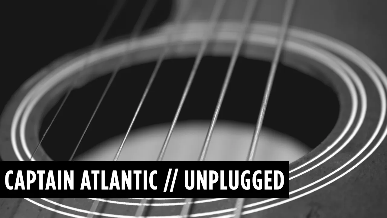 Close-up of an acoustic guitar sound hole and strings with text Captain Atlantic // Unplugged.